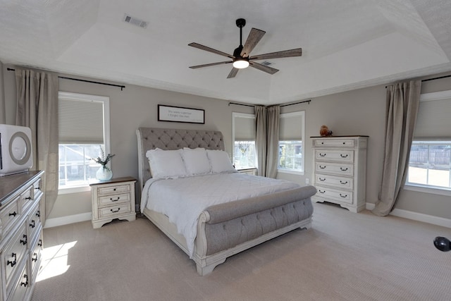 carpeted bedroom with ceiling fan and a raised ceiling