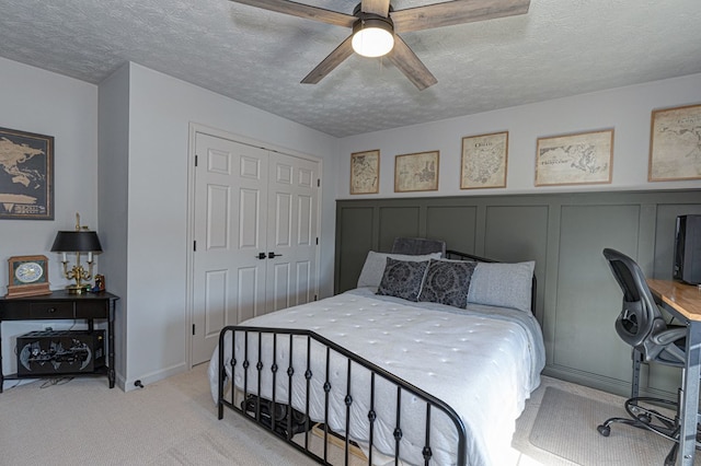 bedroom featuring ceiling fan, light colored carpet, a closet, and a textured ceiling