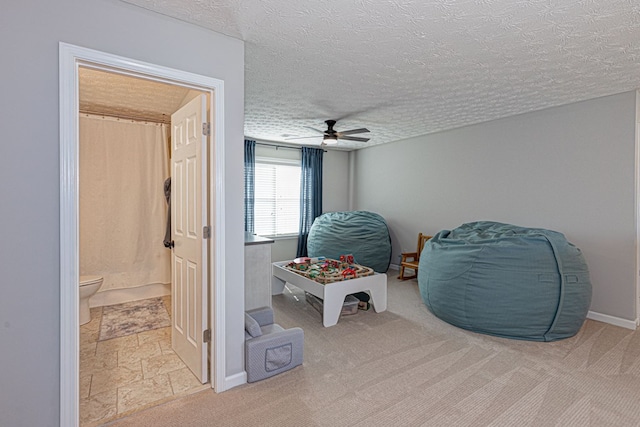 sitting room with ceiling fan, light carpet, and a textured ceiling