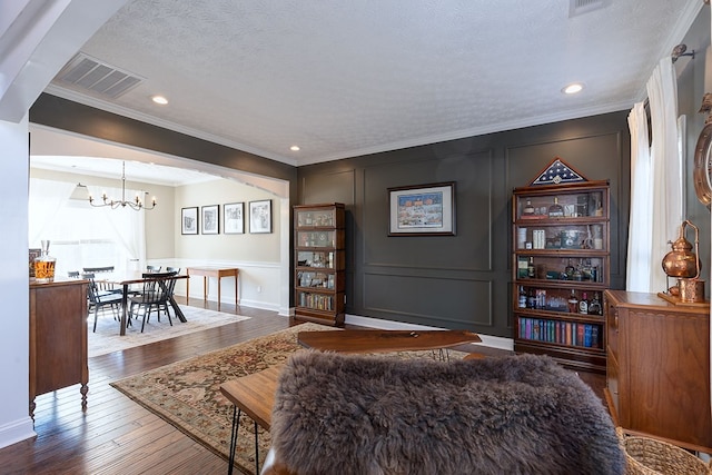 living room featuring hardwood / wood-style floors, a textured ceiling, ornamental molding, and a chandelier