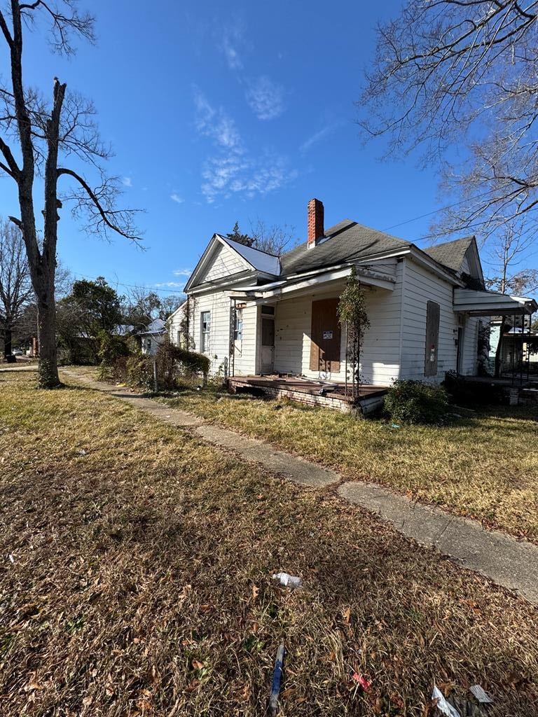 view of side of property with a porch and a lawn