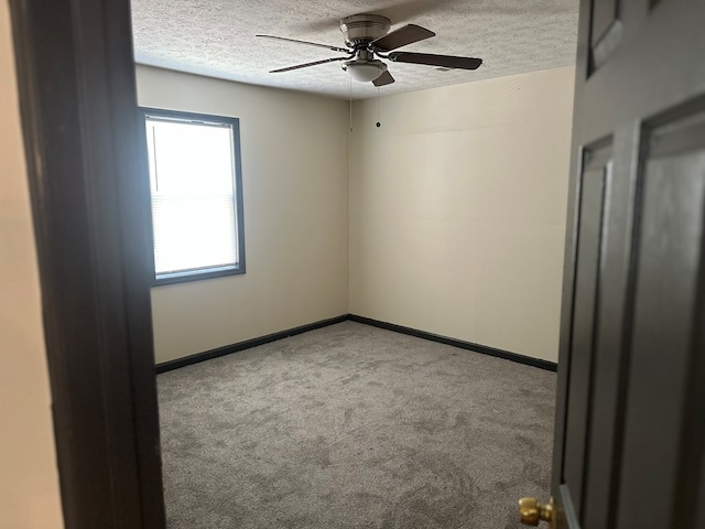 carpeted empty room with baseboards, ceiling fan, and a textured ceiling