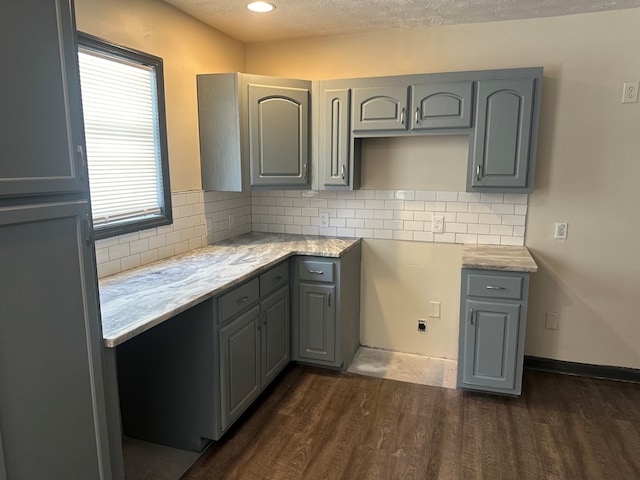 kitchen with a textured ceiling, dark wood finished floors, decorative backsplash, and gray cabinets