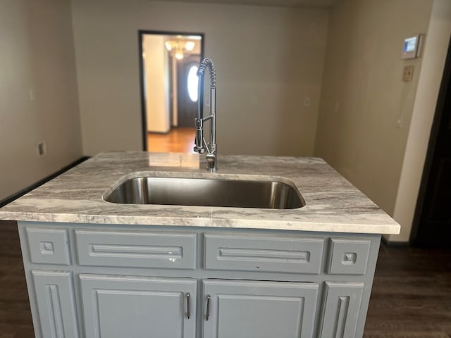 kitchen featuring light stone counters, dark wood-style floors, and a sink