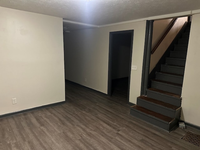 empty room with baseboards, a textured ceiling, wood finished floors, and stairway
