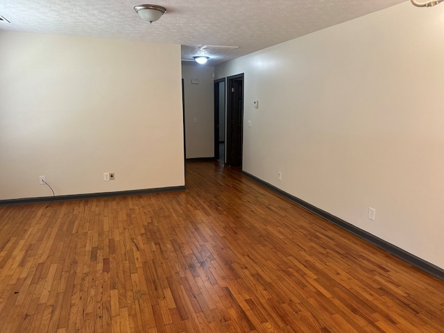 unfurnished room with a textured ceiling, baseboards, and hardwood / wood-style flooring
