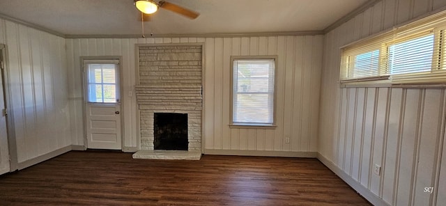 unfurnished living room with ceiling fan, dark hardwood / wood-style floors, a stone fireplace, and ornamental molding