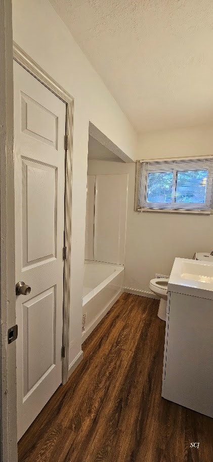 full bathroom with toilet, vanity, hardwood / wood-style flooring, shower / bath combination, and a textured ceiling