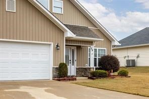 entrance to property with central AC unit, concrete driveway, and an attached garage