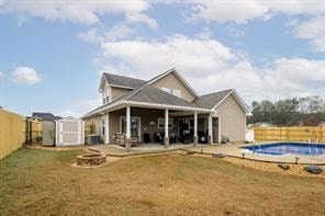 rear view of property featuring a fire pit, a fenced backyard, a storage shed, and an outdoor structure