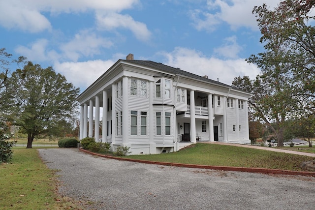 neoclassical home with a balcony and a front yard