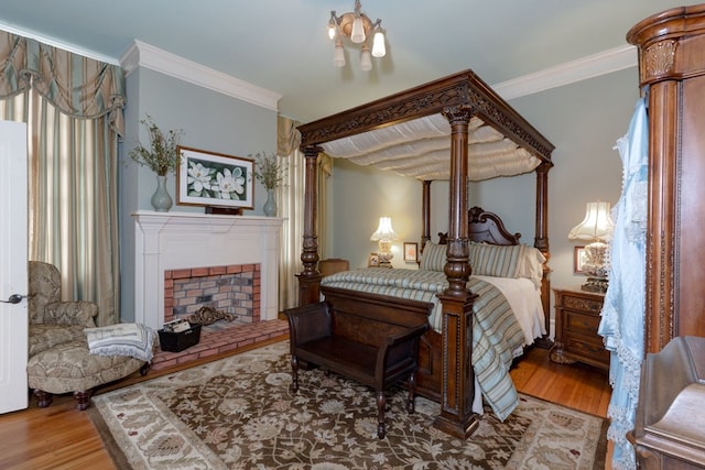 bedroom with hardwood / wood-style floors, ornamental molding, and a fireplace