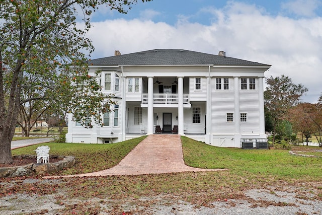 view of front of property featuring cooling unit, a balcony, and a front lawn