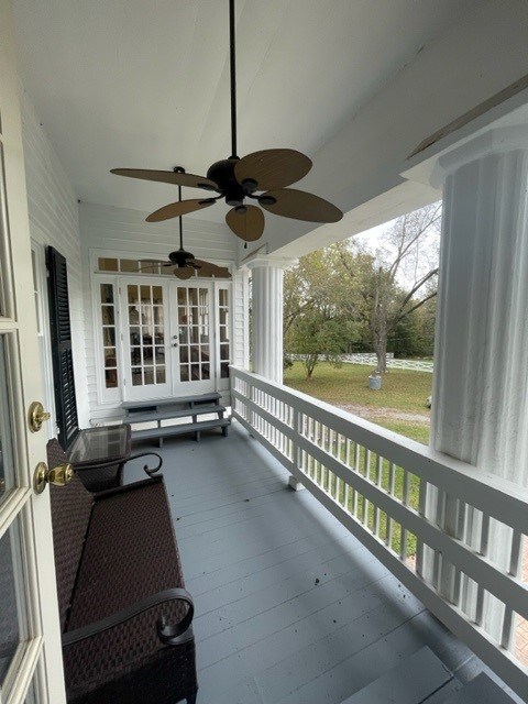 wooden terrace with ceiling fan, a porch, and french doors