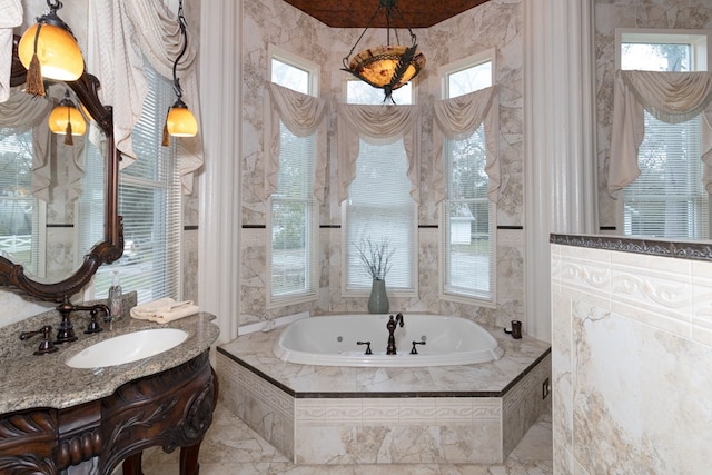 bathroom featuring tiled tub, sink, and a healthy amount of sunlight