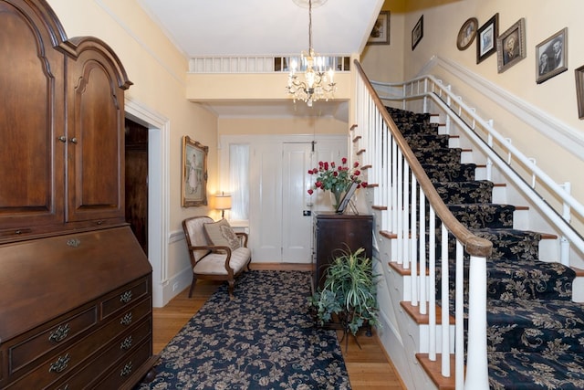 foyer with light hardwood / wood-style flooring, ornamental molding, and an inviting chandelier