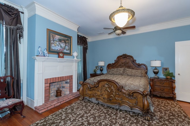 bedroom featuring a fireplace, wood-type flooring, ceiling fan, and crown molding