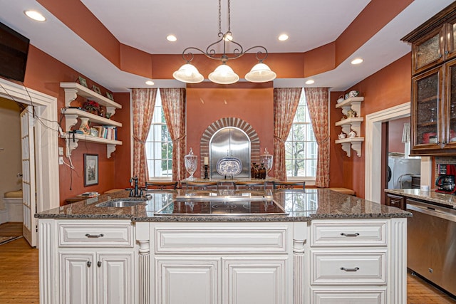 kitchen with pendant lighting, a center island with sink, black electric stovetop, stainless steel dishwasher, and light wood-type flooring