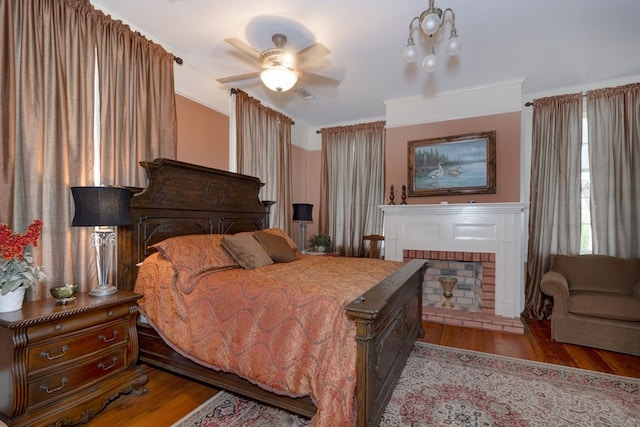 bedroom featuring ceiling fan, light hardwood / wood-style floors, ornamental molding, and a fireplace