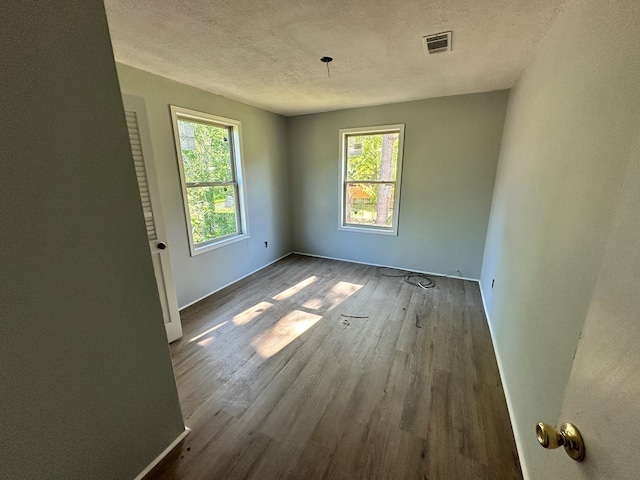 empty room with visible vents, wood finished floors, and a textured ceiling