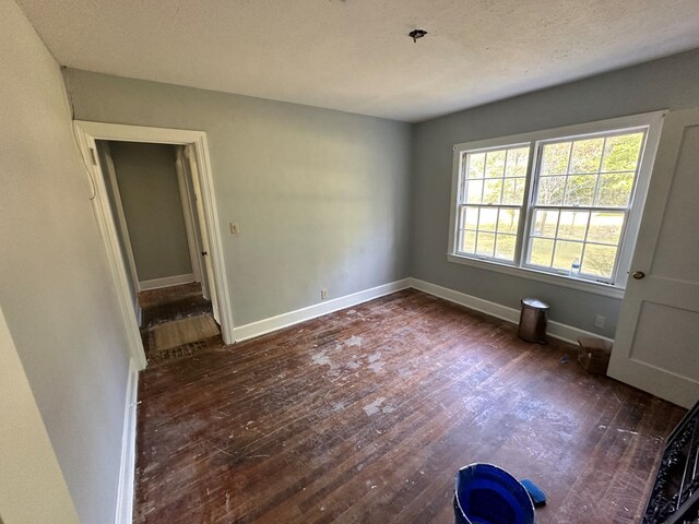 unfurnished room with hardwood / wood-style floors, baseboards, and a textured ceiling
