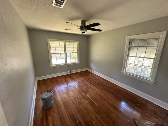 spare room with dark wood finished floors, baseboards, ceiling fan, and visible vents