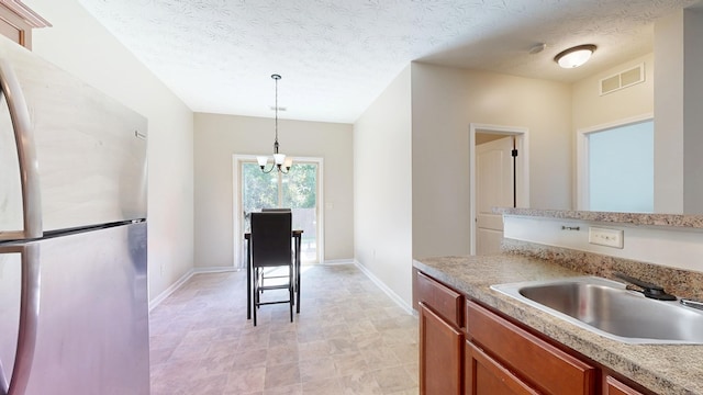 650 Upland Ct, Columbus, GA 31907 - kitchen with freestanding refrigerator, a sink, baseboards, brown cabinetry, and decorative light fixtures
