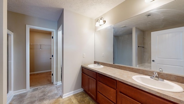 650 Upland Ct, Columbus, GA 31907 - bathroom featuring double vanity, a walk in closet, a shower, and a textured ceiling