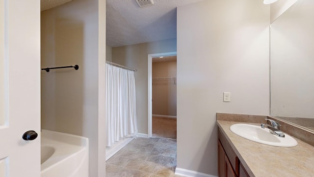 650 Upland Ct, Columbus, GA 31907 - bathroom featuring vanity, baseboards, a bath, a textured ceiling, and a walk in closet