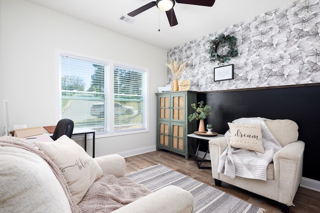 sitting room with baseboards, a ceiling fan, visible vents, and an accent wall