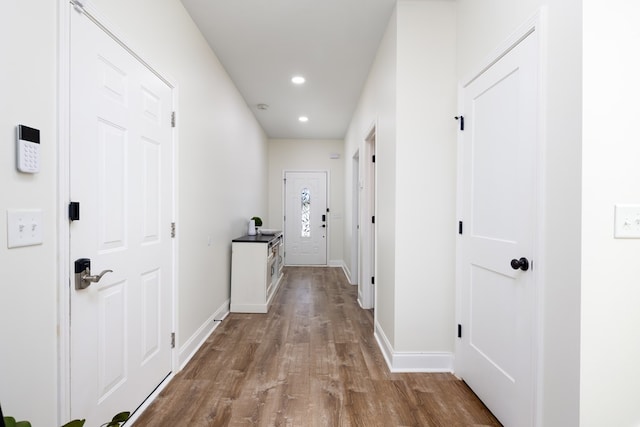 corridor with recessed lighting, wood finished floors, and baseboards