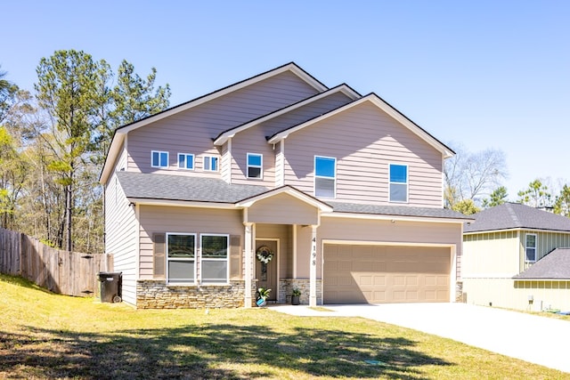 craftsman house with fence, a front lawn, concrete driveway, an attached garage, and stone siding