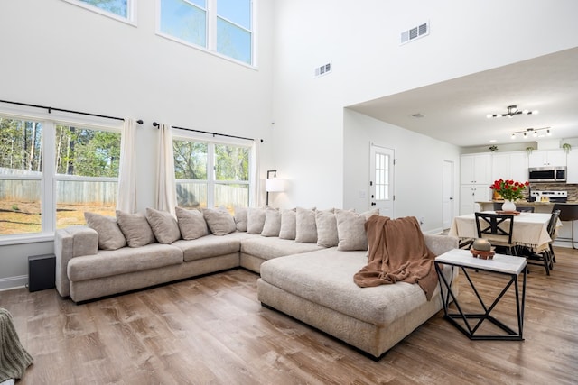 living area featuring a high ceiling, visible vents, and a wealth of natural light