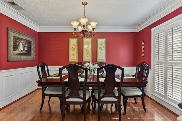 3406 Seminole Dr, Columbus, GA 31907 - dining area with a chandelier, wood-type flooring, crown molding, a textured ceiling, and a wainscoted wall