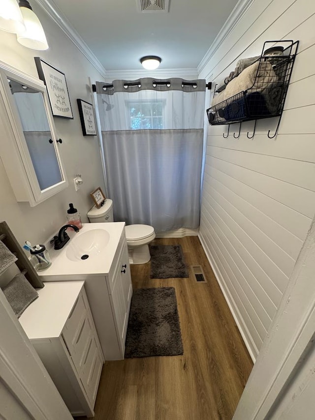 bathroom featuring toilet, wood-type flooring, ornamental molding, vanity, and a shower with shower curtain