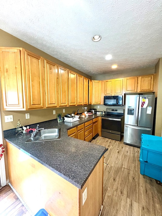 102 Parker St, Lagrange, GA 30240 - kitchen with stainless steel appliances, light wood-type flooring, a peninsula, a textured ceiling, and dark countertops