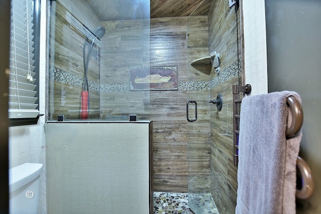 bathroom featuring toilet and a shower with shower door