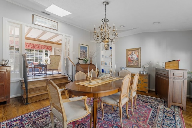 dining room with hardwood / wood-style flooring, an inviting chandelier, crown molding, and a skylight