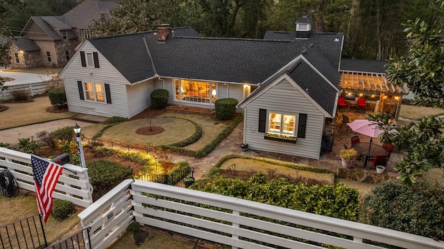 view of front of house featuring roof with shingles, a chimney, and fence