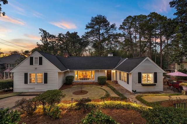 view of front facade with a patio, roof with shingles, and driveway