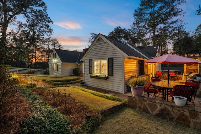 back of house at dusk with a patio area and fence