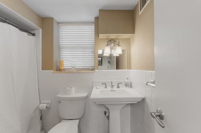 bathroom with a shower with shower curtain, toilet, and tile walls