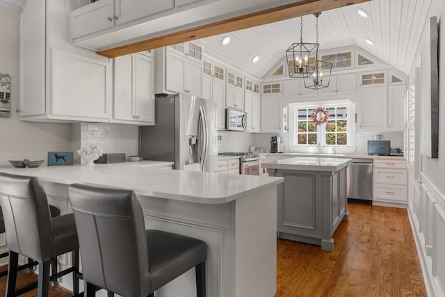 kitchen featuring a kitchen bar, appliances with stainless steel finishes, white cabinets, and kitchen peninsula