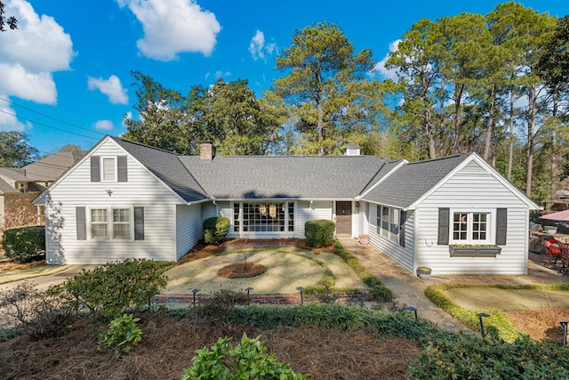 ranch-style home featuring a shingled roof and a chimney