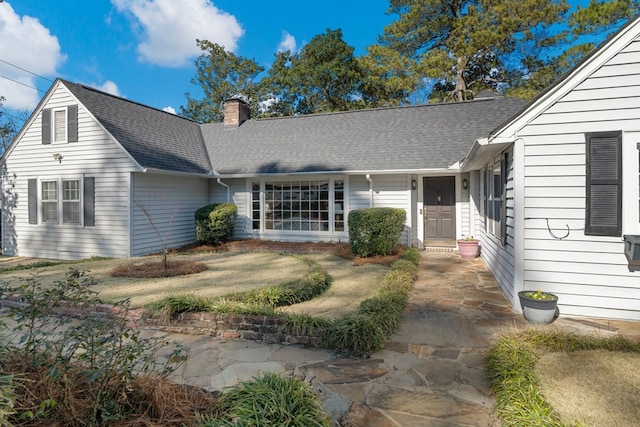 property entrance featuring a shingled roof and a chimney