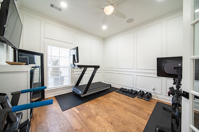 exercise room with visible vents, a decorative wall, and wood finished floors