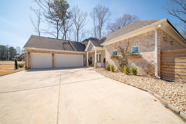 view of front of property featuring a garage, concrete driveway, brick siding, and a shingled roof