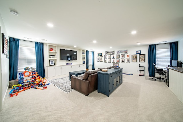 living area featuring built in shelves, recessed lighting, light colored carpet, and visible vents