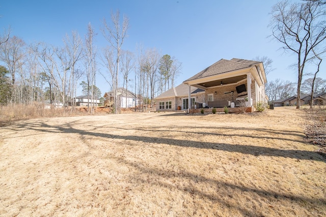 back of property with covered porch, a yard, and brick siding