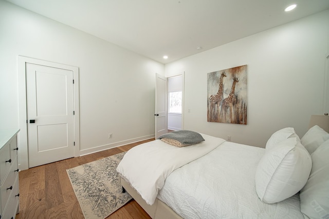 bedroom with baseboards, wood finished floors, and recessed lighting